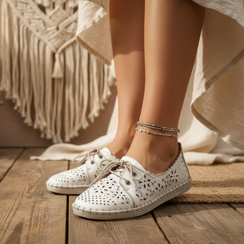 White boho lace up shoe with floral patterns on a tan background
